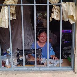 Tailor at work, smiling at us as she works at her Singer machine