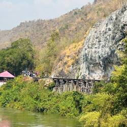 Thamkrasae Railway Bridge clings to the rocky banks of the river