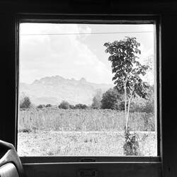 A train window frames the distant mountains