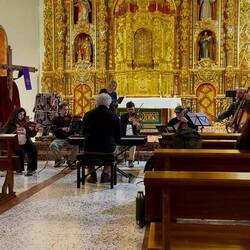Chorus members in the pews; the conductor doubles as an organist.