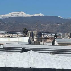 Schnee der Sierra Nevada und im Vordergund weiß von den Folien der Gewächshäuser
