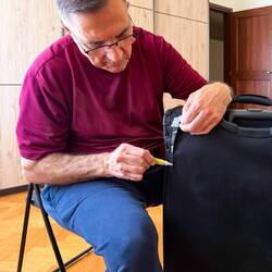 Mui gets to work repairing the tear on the corner of the suitcase — Bologna, Italy.