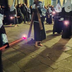Nazareno or penitent carrying one of the heavy crosses barefoot with a chain on his ankle