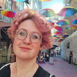 Tiffi steht auf pinker Straße. Über ihr bunte Schirme