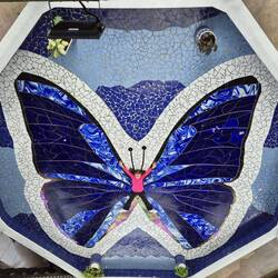 Ein Kind liegt ,kunstvoll' auf dem Schmetterlingsmosaik