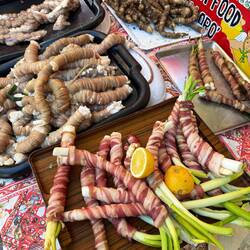 Regionale Spezialitäten, mit Darm umwickeltes Fett und vegane Frühlingszwiebeln im Speckmantel
