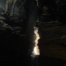 Unter der Erde fällt etwas Licht durch das Gestein, hier kommt der Devis-Fall an