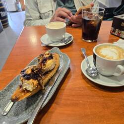 A shared lunch of toast, cheese, sautéed onions, and ham with coffee.
