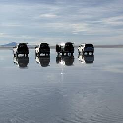 Our faithful Toyota Land Cruisers sit with their images reflected in the water.