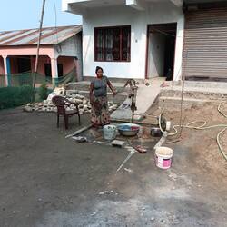 Woman pumping water in front of her house