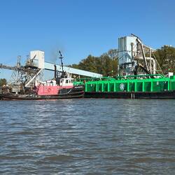 Tug pushing a barge into the dock.