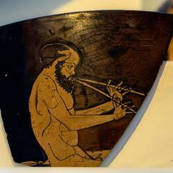 Fragment from Attic red-figure skyphos ... Satyr playing double pipes (500-475 BC).