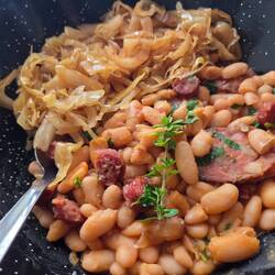 Beans cooked with Spanish sauce and local sausage with fermented cabbage