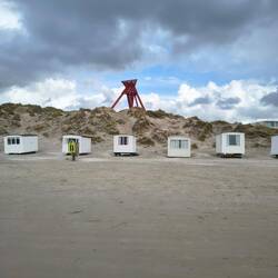 Ein blaues Loch am Himmel über den Strandhütten und dem Wahrzeichen von Blokhus
