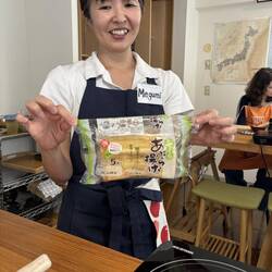 Die Kochlehrerin zeigt den gekauften frittierten Tofu für die Maki-Rolle.