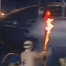 Der Skispringer mit der Olympischen Fackel auf der Schanze