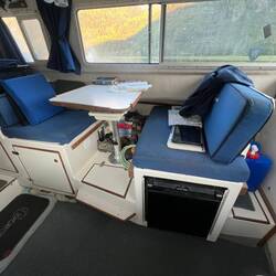 Dinette table. Refrigerator under forward seat. Seat back is convertible to face table or window.