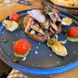 Pork on a grilled sweet potato with artichokes, tomato, capers, and pesto. So good!