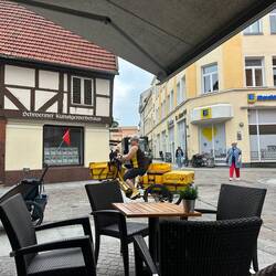 Die Postbotin flitzt mehrmals an unserem Frühstückstisch und auch sehr nah an den Passanten vorbei.