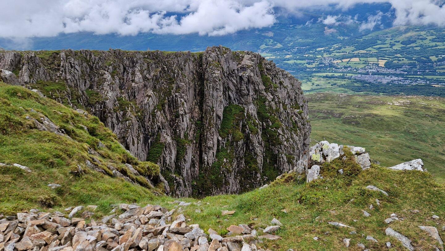 Dramatic cliff with Dolgellau in the distance viewed from Mynydd Moel