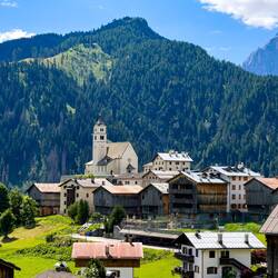 Old wooden buildings are interspersed with modern structures — Colle Santa Lucia, Italy.