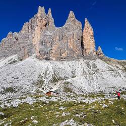 That's me in the coral jacket — Tre Cime and the Refugio Lavaredo.
