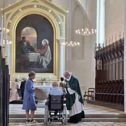 Der Pastor hat nochmals extra liturgische Gewänder zum Abendmahl übergezogen. Hier erhält der Rolli.