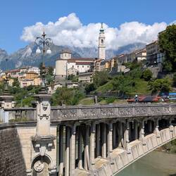 Belluno hinter der Brücke Ponte della Vittoria und vor den Alpen.