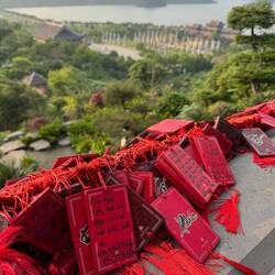 Red wooden prayers softly rattled on their ribbons as they caught the warm breeze.