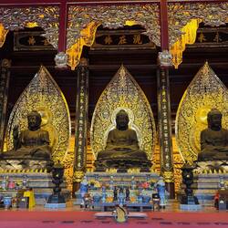 Lilz sits in front of 3 colossal Buddha statues representing the past, present and future