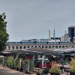 A train on Pont D'Bercy with the restaurant s in the foreground