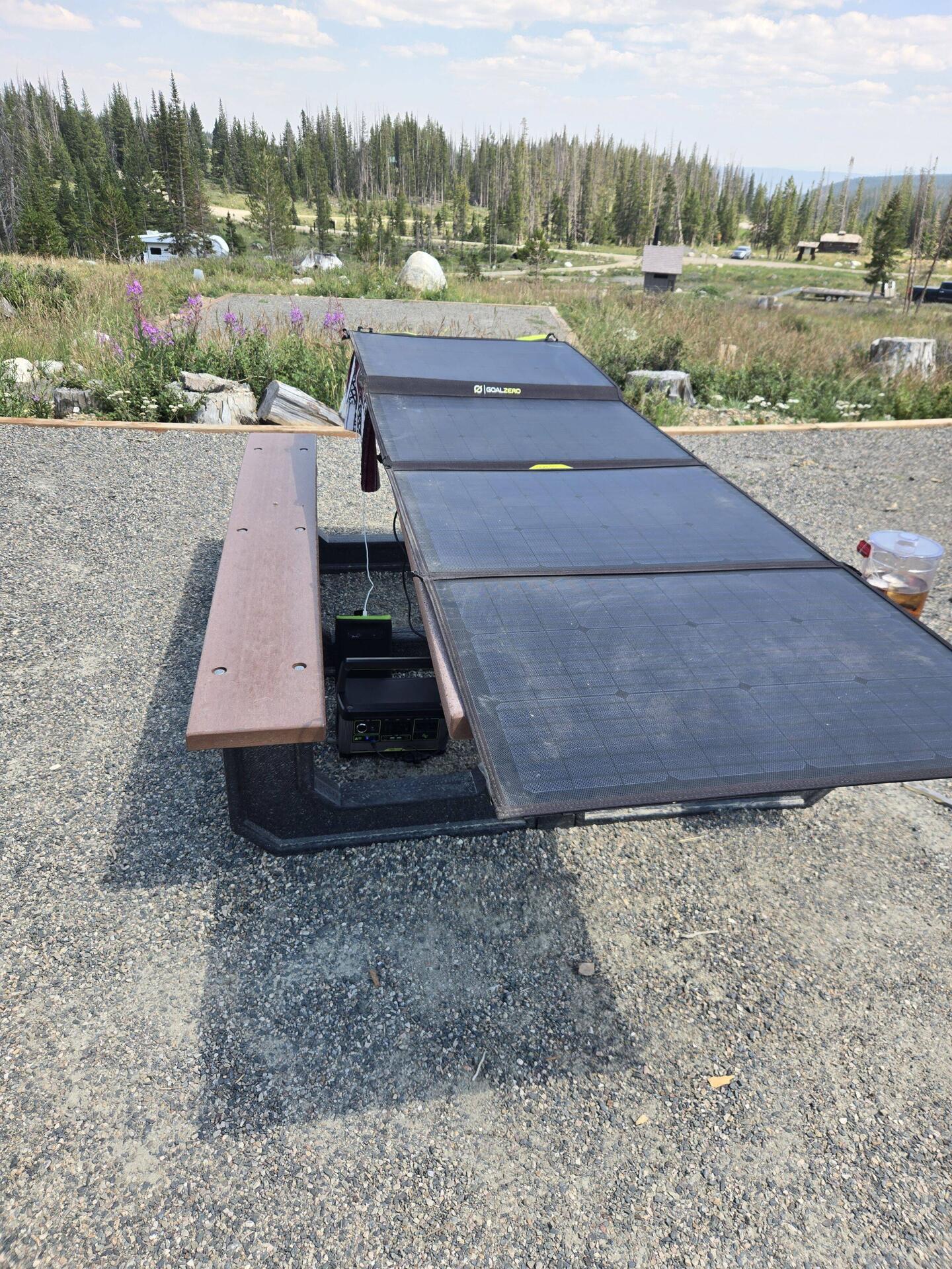 Solar panel on the picnic table with batteries connected underneath.