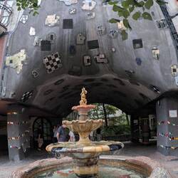 The Hundertwasserhaus in Vienna features wavy lines, vibrant mosaics, and trees growing from balconi