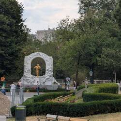 Gilded statue of composer Johann Strauss II in Vienna's Stadtpark, framed by a marble arch.