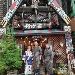 In Ainu-Tracht vor seinem Laden
