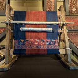 upright wooden loom with a schematic of the pattern for the weaver