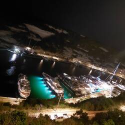 Night time view of the marina from the old town above with a spectacular illuminated motor yacht