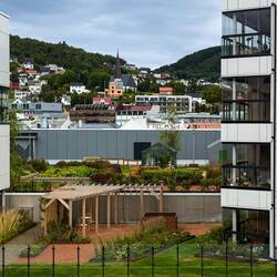 A peek through the buildings of the apartment complex reveals a larger communal garden.