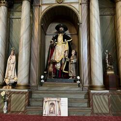 San Roque, in his trademark pilgrim garb and left leg exposed to show his plague affliction