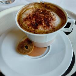 Cappucino with the madeline hiding under the cup
