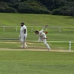 The bowler runs as he throws the ball towards the batter.
