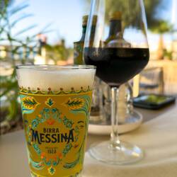 Cheers with a local beer and a glass of red wine — Cefalù, Sicily.