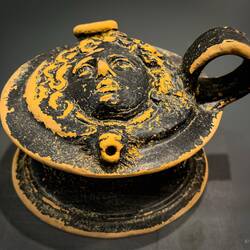 A guttos (liquid jar with spout) with Medusa head in relief (4th-3rd century BCE) — Osterio Magno.