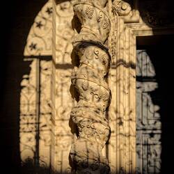 Decorative column framed by the wrought iron door — Duomo di Siracusa.